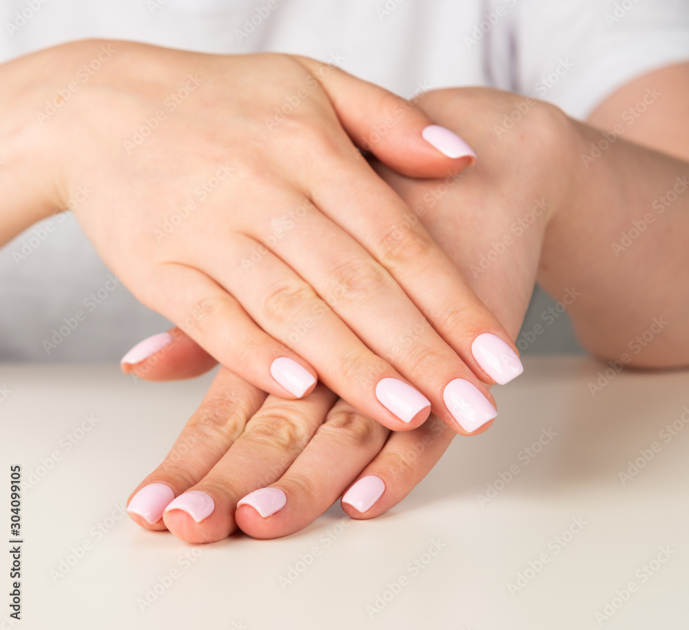 Beautiful female hand with light pink nail design..