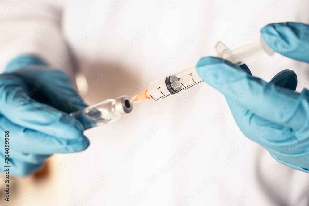Doctor or nurse hand with nitrile glove holding flu, measles vaccine for baby vaccination, medicine and drug concept Doctor or nurse hand with nitrile glove holding flu, measles vaccine for baby vaccination, medicine and drug concept