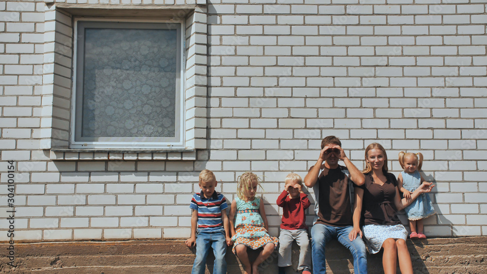A large family with four children in front of their own home.