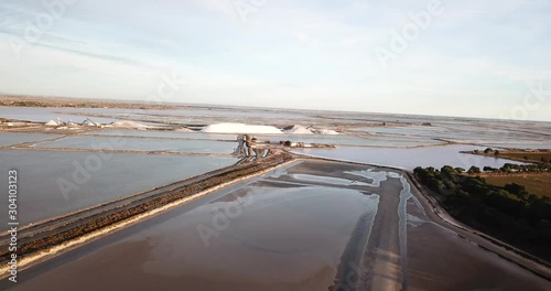 vol au dessus des marais salant au coucher de soleil avec tas de sels (camels)  au loin avec eau et chemins de terre entre les différents étangs photo