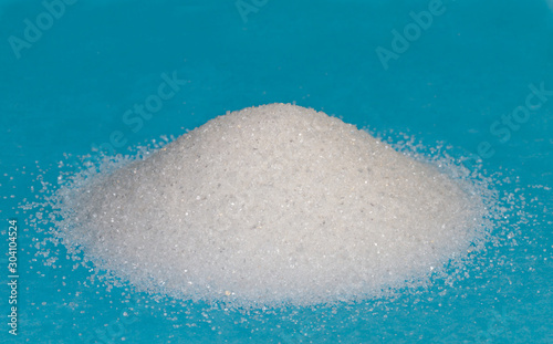 Heap of white granulated sugar on a blue background