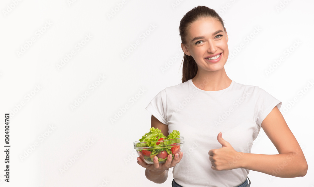 Woman Holding Vegetable Salad Standing Gesturing Thumbs-Up, White Background Woman Holding Vegetable Salad Standing Gesturing Thumbs-Up, White Background