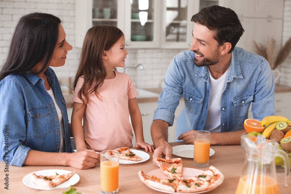wife, husband and daughter having pizza for lunch at home