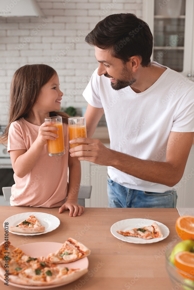 father clicking glasses with orange juice with daughter in the kitchen father clicking glasses with orange juice with daughter in the kitchen