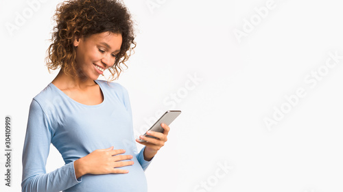 African-american pregnant woman messaging on cellphone, free space
