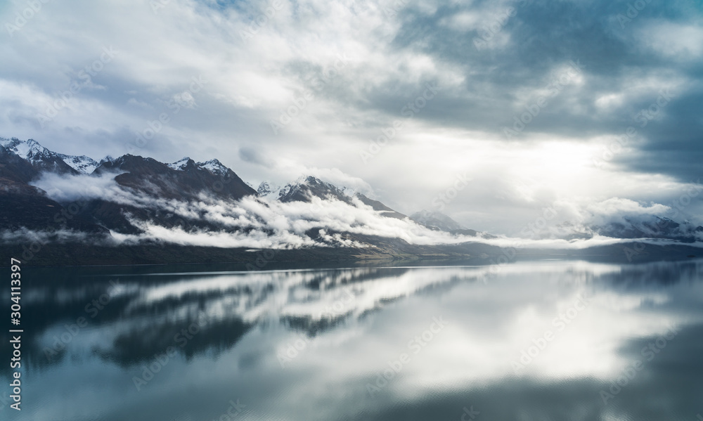 Sky and mountains reflect in Lake Wakatipu near Queenstown. Moody New Zealand. Landschaft in Neuseeland Sky and mountains reflect in Lake Wakatipu near Queenstown. Moody New Zealand. Landschaft in Neuseeland
