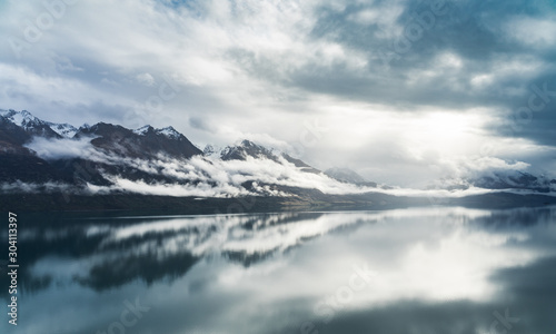 Sky and mountains reflect in Lake Wakatipu near Queenstown. Moody New Zealand. Landschaft in Neuseeland