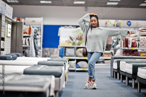 Mattress shop. African woman choosing the right furniture for her apartment in a modern home furnishings store.