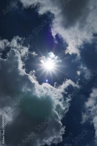 Dark blue sky with clouds and sun