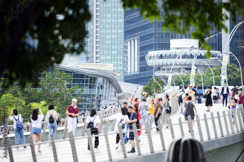 Obraz na płótnie (Focus on the background) Defocused crowd of local people and tourists walking on a bridge in Singapore. Singapore is an island city-state off southern Malaysia. w salonie
