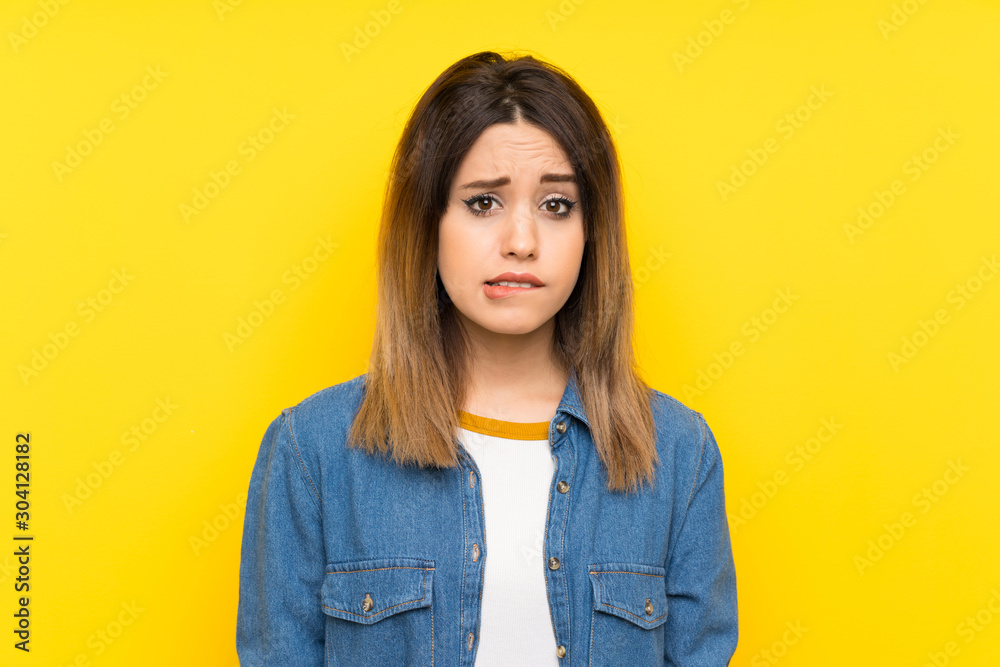 Young woman over yellow background having doubts and with confuse face expression Young woman over yellow background having doubts and with confuse face expression
