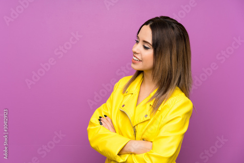 Young woman over purple background looking to the side