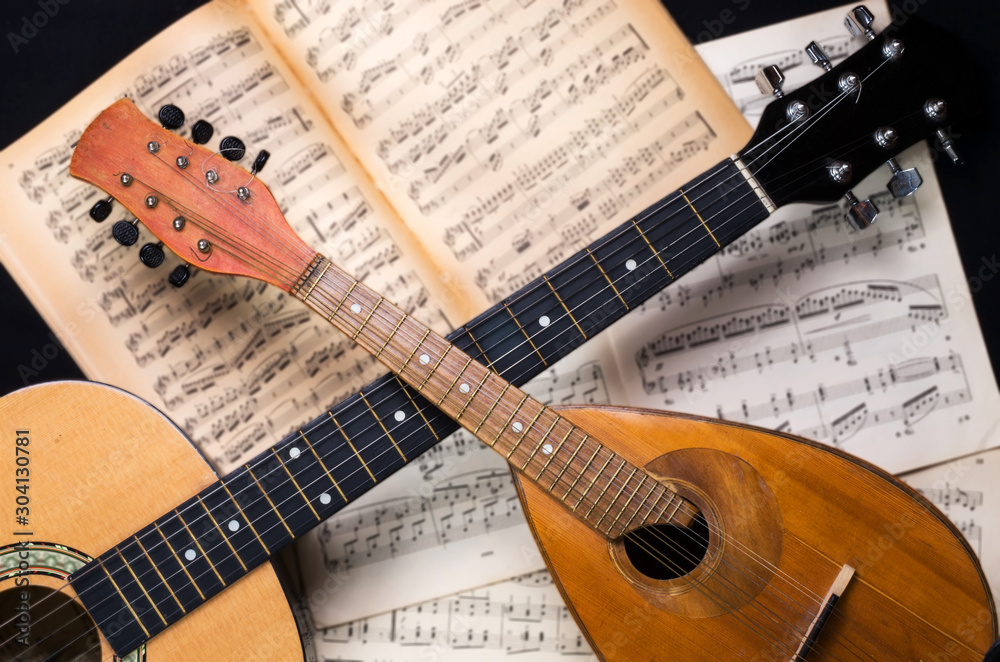 Mandolin and guitar with blurred sheet music books on a black background.  Stringed musical instruments. foto de Stock | Adobe Stock