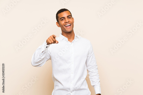 Young handsome brunette man over isolated background surprised and pointing front