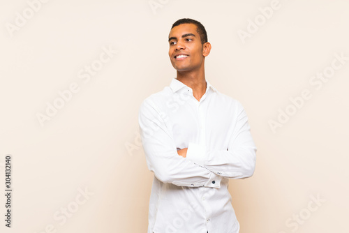 Young handsome brunette man over isolated background with arms crossed and happy