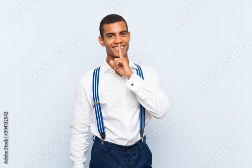 Young handsome brunette man with suspenders over isolated background doing silence gesture