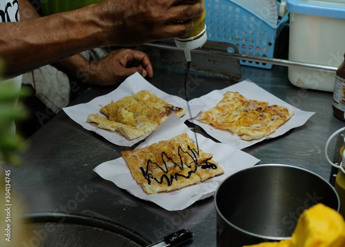 Cooking banana pancakes or roti with chocolate and condensed milk photo