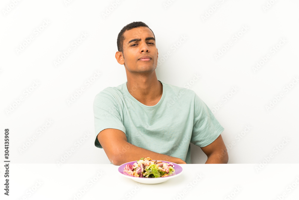 Young handsome man with salad in a table standing and looking to the side Young handsome man with salad in a table standing and looking to the side