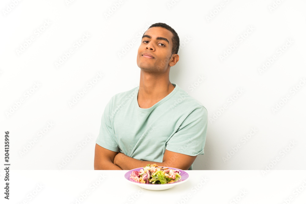 Young handsome man with salad in a table laughing