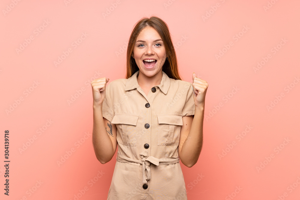 Lithuanian blonde girl over isolated pink background celebrating a victory in winner position Lithuanian blonde girl over isolated pink background celebrating a victory in winner position