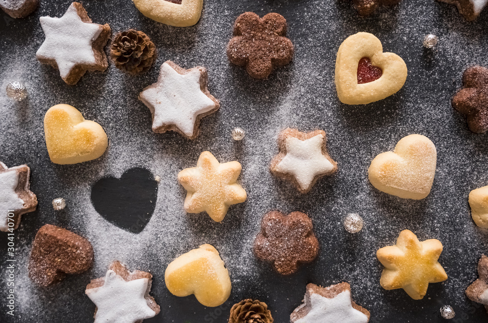 Assorted Christmas cookies with powdered sugar on the dark background, top view Assorted Christmas cookies with powdered sugar on the dark background, top view