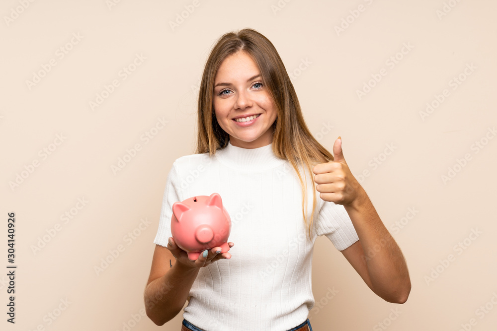 Young blonde woman over isolated background holding a big piggybank Young blonde woman over isolated background holding a big piggybank