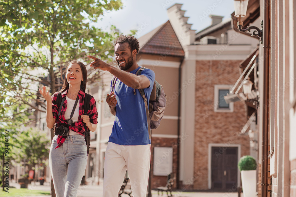asian woman and african american man walking no the city and pointing on something asian woman and african american man walking no the city and pointing on something