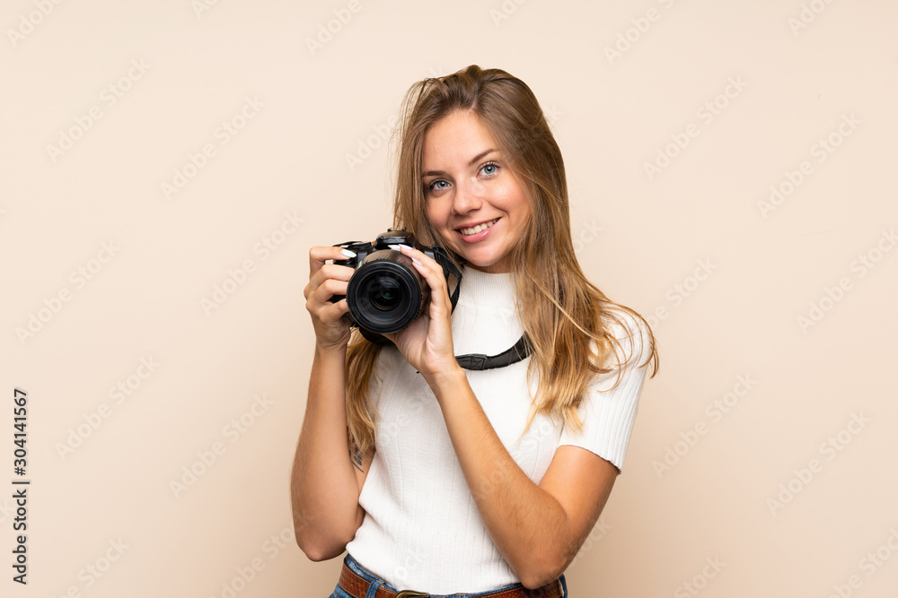 Young blonde woman over isolated background with a professional camera Young blonde woman over isolated background with a professional camera