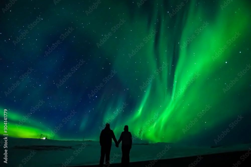 A silhouette of a couple with the northern lights in the background, in Iceland.