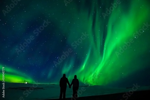 A silhouette of a couple with the northern lights in the background, in Iceland.