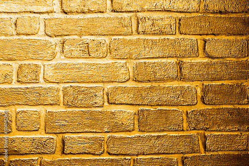 Golden background based on the image of a brick wall tinted in gold