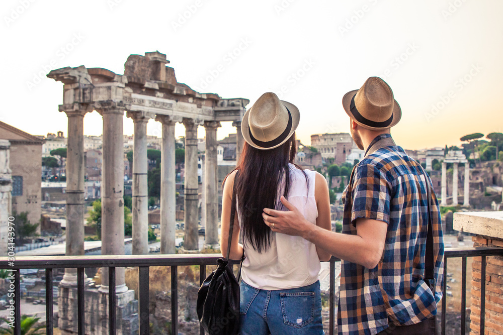 Young couple tourist looking at Roman Forum at sunrise hugging. Historical imperial Foro Romano in Rome, Italy from panoramic point of view.