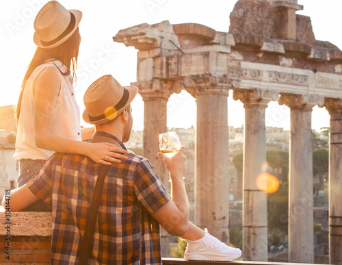 Canvas Print Young couple tourist with glass of white wine at Roman Forum at sunrise