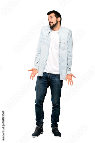 Full-length shot of Handsome man with beard making doubts gesture looking side over isolated white background © luismolinero