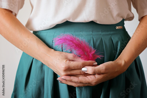 A woman's hands holding a pink feather at belly . Woman healthcare, gynecology and hygeine concept