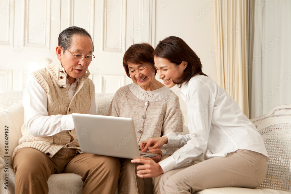 PCを操作する仲の良いシニア夫婦と娘