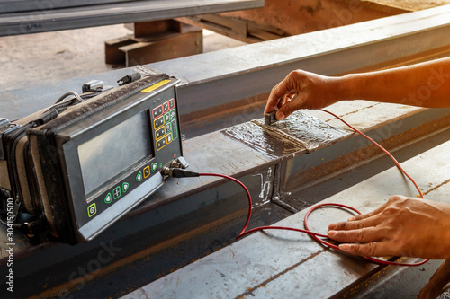 Checking defect in welded of steel add joint with process Ultrasonic testing (UT) of Non-Destructive Testing(NDT), focus on hand that conducts the welding test.
