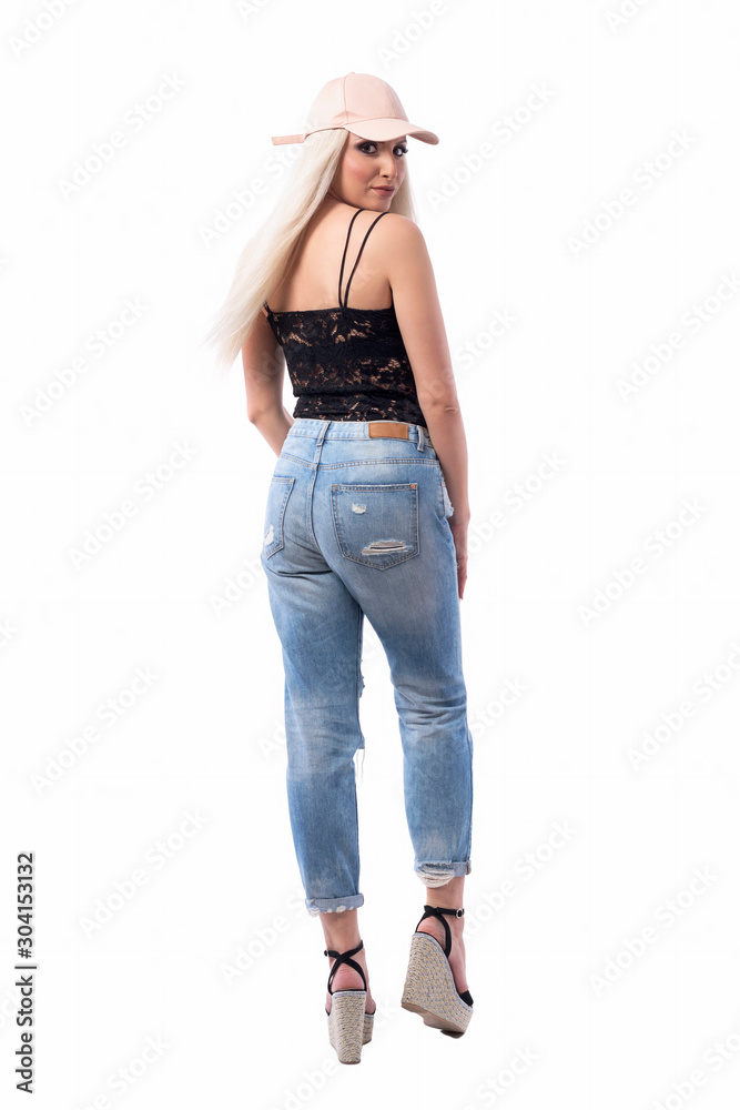 Back view of confident young blond hair woman with cap turning and looking at camera with smile. Full body isolated on white background. Back view of confident young blond hair woman with cap turning and looking at camera with smile. Full body isolated on white background.