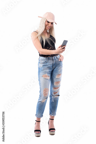 Happy relaxed young modern style casual blonde girl using smart phone or taking photos. Full body isolated on white background. photo