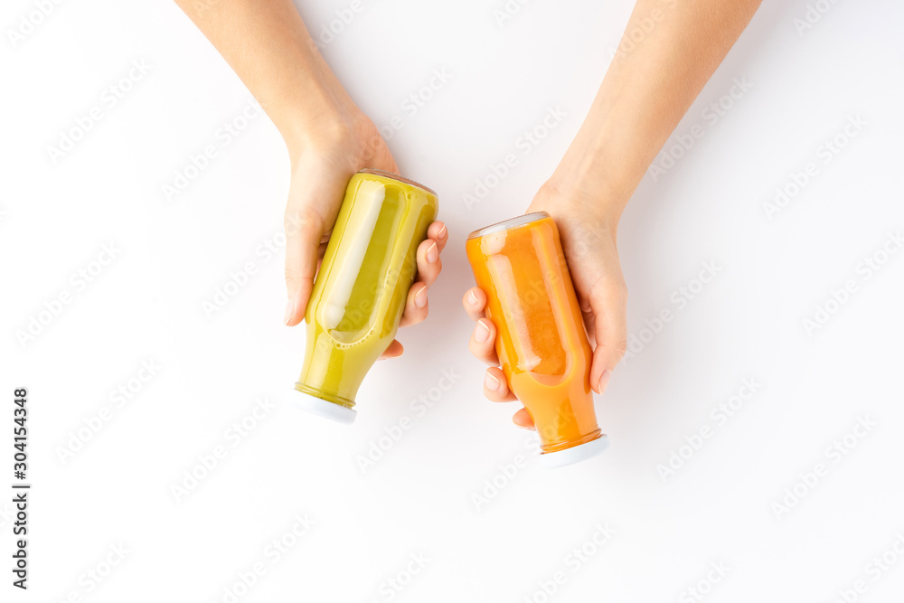 Overhead shot of woman’s hands holding bottles of fruit and vegetable juices isolated on white background