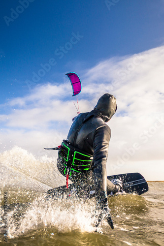 Kiteboarder shredding on the German Sea during a beautiful day in February in St. Peter Ording, Germany photo