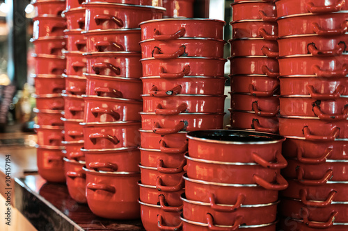 Stack of assorted red ceramic and steel cooking pans © Elena Sistaliuk