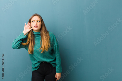 young pretty woman looking serious and curious, listening, trying to hear a secret conversation or gossip, eavesdropping photo