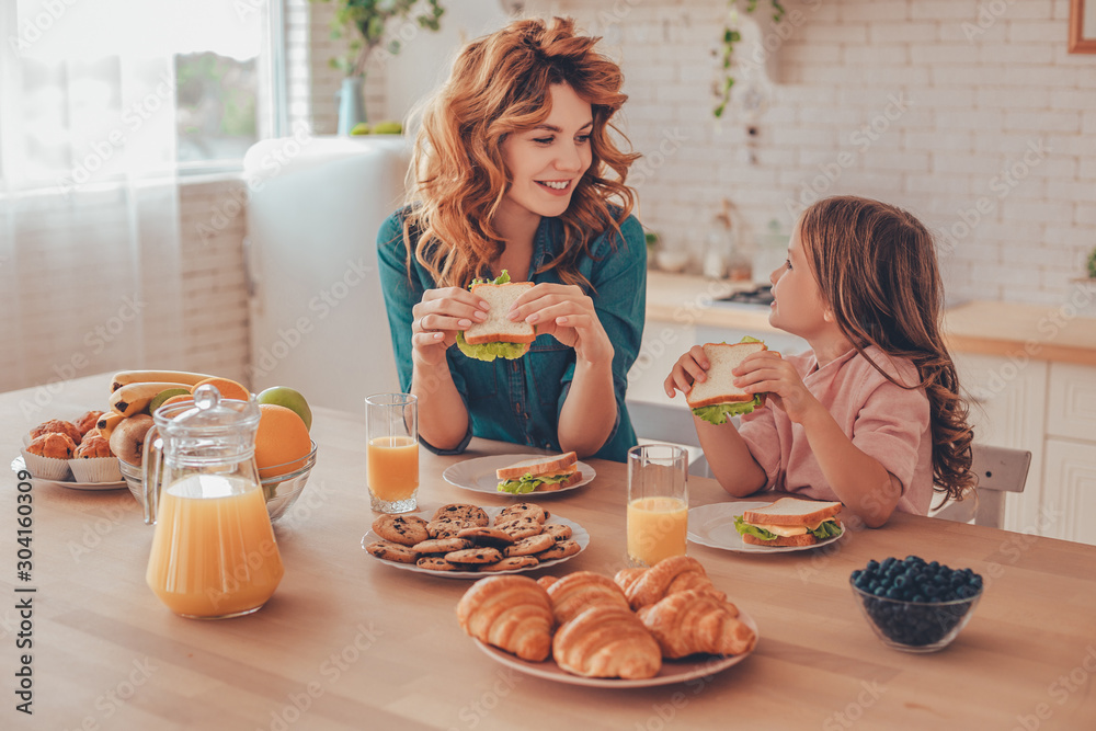 Fotografie cute girl and young woman having sandwiches for breakfast together