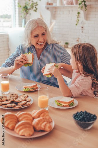 smiling senior woman having breakfast with little girl together