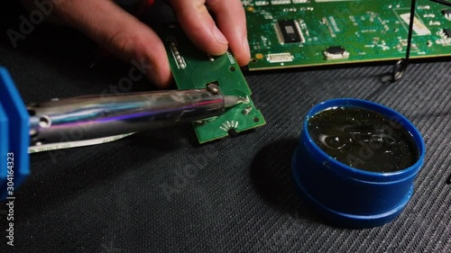 Young engineer soldering a board. View from above