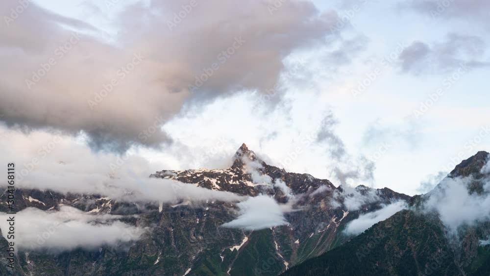 Cloud pass though peak mountains with white snow and green grass in summer season in india Cloud pass though peak mountains with white snow and green grass in summer season in india