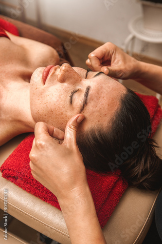 Alternative Medicine. Therapist healing lying woman smiling calm close-up doing face massage