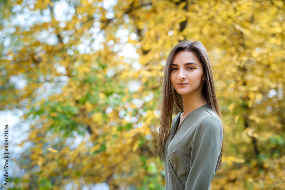 Female portrait. Brunette woman portrait in autumn park wearing olive dress