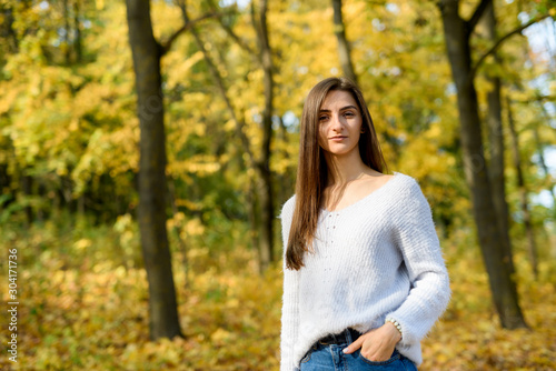 Portrait of brunette woman in casual wear in autumn park. Yellow colours around beautiful woman